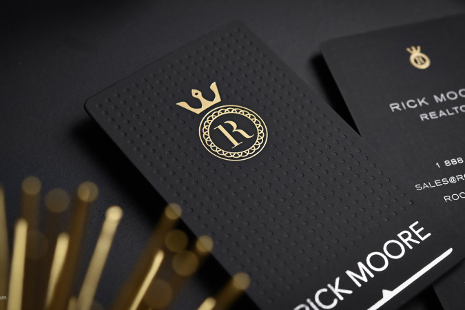 Black suede business cards with gold foil crown monogram, debossed dot texture, and bold white text for a luxurious, professional presentation.
