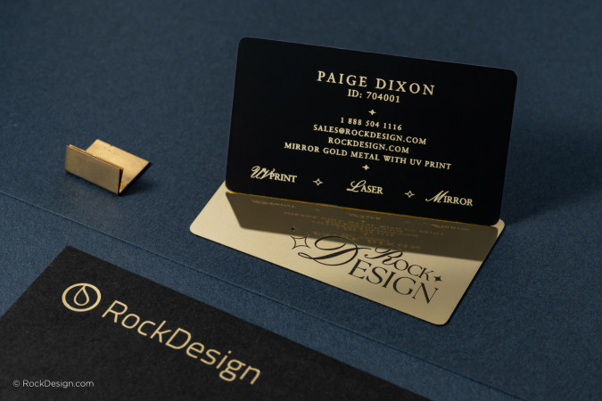 Black and gold metal business cards with mirror finish and UV printed text, displayed on dark stationery for luxury branding and design.