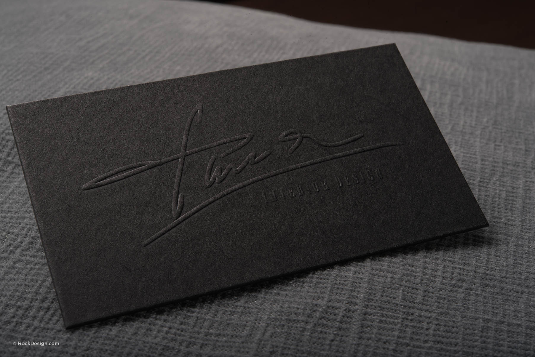Luxury black business card with embossed logo on textured surface, showcasing premium black duplex uncoated stock.