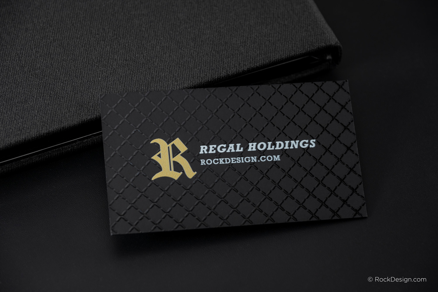 A luxury black business card for "Regal Holdings" with a gold Gothic-style "R" logo and white UV-printed text for the company name and website.