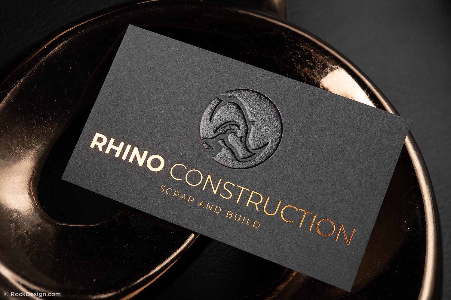 Black premium business card with copper foil text and embossed rhino logo for Rhino Construction